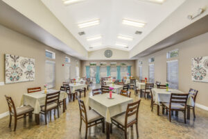 Interior dining hall, 12 four seat tables, tile floor, vaulted ceiling, neutral toned walls, patterned wall art.