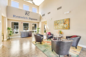 Interior Renwick Square Lobby, Neutral toned walls, four lounge chairs, coffee table, contemporary area rug, abstract painting on wall, renwick square signage on wall, high ceilings.
