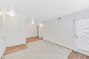 Interior Unit Living Room, Wood floors around doorways, neutral toned carpeting, white walls.