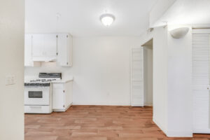 Interior Unit Kitchen, Wood Floors, White walls, white appliances, white cabinetry.