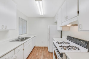 Interior Unit Kitchen, Wood Floors, White appliances, stainless steel sink, white cabinets.
