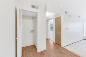 Interior Unit Hallway, Wood floors, Linen closet with Washer and dryer hookups, white walls.